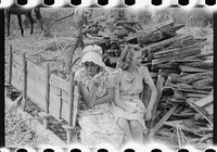 Mountaineer's wife and daughter sitting on the sled in which wood is hauled to boil the sap for making cane sorghum syrup. They are waiting for "syrupping off" time when many members of the community join in eating it. On the highway between Campton and Jackson, Kentucky. Sourced from the Library of Congress.