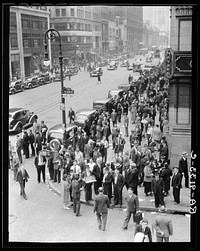 Background for Hightstown project photographs. Seventh Avenue and West 28th Street, New York. Garment workers leave the factories for noon hour by Dorothea Lange