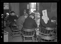 Weighing-in room of the stockyards. Aledo, Illinois. Farmers sitting around the stove enjoying themselves and getting warm. The stove is still a middle western institution by Russell Lee