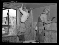 Installing wallboard in a house at the Greenhills project, Ohio. Note sound proofing and insulation by Russell Lee