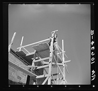 A load of brick going up the building chimney of a house under construction at Greendale, Wisconsin by Russell Lee