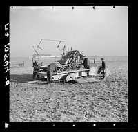 Binder loaded on a truck, preparatory to moving it. The rear wheels of the truck were lowered by digging pits to facilitate loading the binder. Raymond Zink, tenant farmer, is moving from one farm to another twenty-four miles away. Near Templeton, Indiana by Russell Lee