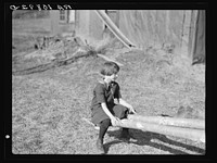 One of the Max Sparks' children playing on homemade teeter-totter near Long Lake, Wisconsin by Russell Lee