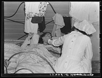 Tulare County, California. Farm Security Administration (FSA) camp for migratory agricultural workers at Farmersville. Nurse of Agricultural Workers' Health and Medical Association attends sick migrant woman while awaiting doctor. Sourced from the Library of Congress.