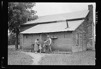 [Untitled photo, possibly related to: Tobacco sharecropper and his family at the back of their house showing kitchen door, household equipment, foot path to barn. Person County, North Carolina]. Sourced from the Library of Congress.