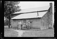 [Untitled photo, possibly related to: Tobacco sharecropper and his family at the back of their house showing kitchen door, household equipment, foot path to barn. Person County, North Carolina]. Sourced from the Library of Congress.
