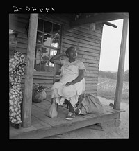 [Untitled photo, possibly related to: Mother of sharecropper family and friend coming up the road in the rain, bringing home sacks of vegetables from the neighbor place. Person County, North Carolina. Off Highway 144]. Sourced from the Library of Congress.