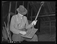Barn boss cleaning shovel at logging camp near Effie, Minnesota by Russell Lee