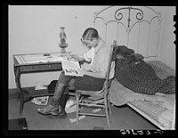 Boy reading in bedroom. Note lack of proper bed clothing. Home of A.O. Ryland near Williston, North Dakota by Russell Lee