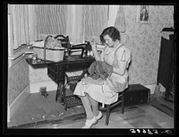 Mrs. Carl Thorson patching clothes in home. Crosby, North Dakota by Russell Lee