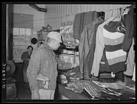Member of Lakeview Cooperative Association examining clothing in general store. Arkansas by Russell Lee