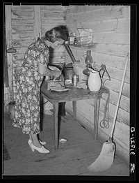 Mrs. Adams, wife of farmer near Morganza, Louisiana, preparing sweet potatoes for dinner. Family will shortly be helped by FSA (Farm Security Administration) by Russell Lee
