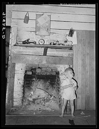 Hairlipped son of Adams family in front of fireplace. Morganza, Louisiana by Russell Lee