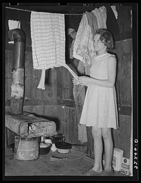 [Untitled photo, possibly related to: Mexican girl standing over pan of hot coal in which pail of water is heating. Robstown, Texas] by Russell Lee
