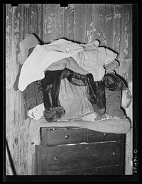 Clothing piled atop bureau in Mexican house in San Antonio, Texas. There is lack of closet space in the houses of Mexicans by Russell Lee