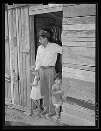 Mexican father and children in doorway of their home made of scrap lumber. San Antonio, Texas by Russell Lee
