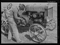 Son of pioneer at El Indio, Texas, repairing clutch on tractor by Russell Lee