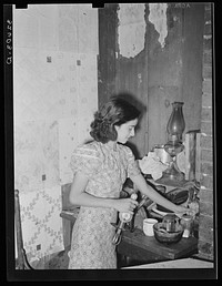 Mexican girl straightening corner of her kitchen. San Antonio, Texas by Russell Lee