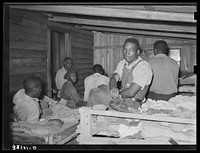 es in bunkhouse in strawberry fields near Hammond, Louisiana. Note crude bunks, straw mattresses, and crowded conditions by Russell Lee