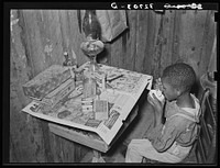 Boy drinking "milk" made of flour and water. He was sick and his mother, the wife of a sharecropper, had given him. Near Marshall, Texas by Russell Lee