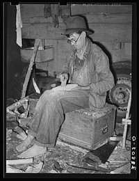 Migrant worker who makes ornaments from horns. He is filing down a wooden block to be used as base for horns. Near Hammond, Louisiana by Russell Lee