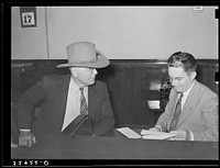 Sheriff of adjoining county talking to cashier in bank. San Augustine, Texas by Russell Lee