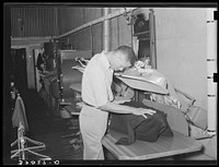 Pressing a coat in tailor shop. San Augustine, Texas by Russell Lee