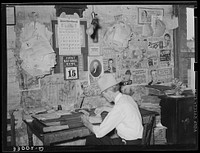 Small grocery store owner surrounded by bills. San Augustine, Texas by Russell Lee