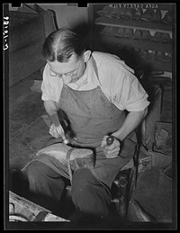 [Untitled photo, possibly related to: Bootmaker pounding wooden peg into sole of boot in building up sole with several pieces of leather. Cowboy boot shop, Alpine, Texas] by Russell Lee