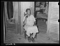 Mother of  agricultural day laborer on porch of her home. She was crippled with rheumatism. Muskogee County, Oklahoma by Russell Lee