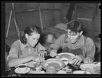 Two agricultural day laborers eating dinner after spending the morning chopping cotton. Beans are the staple fare of these workers. Near Webbers Falls, Oklahoma by Russell Lee