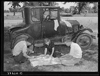 [Untitled photo, possibly related to: Migrant workers eating dinner by the side of their car while they are camped near Prague, Oklahoma. Lincoln County] by Russell Lee