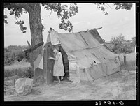Daughter of agricultural day laborer coming out of tent where her uncle slept. Poteau Creek near Spiro, Oklahoma by Russell Lee