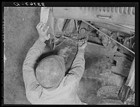 Migrant boy who is somewhat of a mechanic checking up the lighting wires of their improvised truck which will carry them to California. Near Muskogee, Oklahoma by Russell Lee