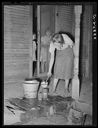 Daughter of tenant farmer near Muskogee, Oklahoma, changing water in goldfish bowl. Refer to general caption number 20 by Russell Lee