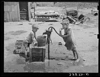 Children of Mays Avenue camp pumping water from thirty-foot well which supplies about a dozen families. Oklahoma City, Oklahoma. Refer to general caption 21 by Russell Lee