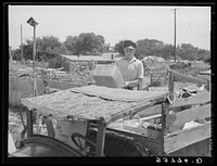Top of oil truck made of old carpets. Boy is unloading discarded crates and overripe vegetables which he found in city market. Oklahoma City, Oklahoma. See general caption no. 21 by Russell Lee