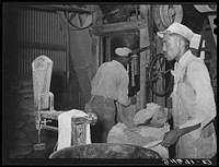 Workers weighing up feed made of peanut shells and strap molasses. Comanche, Texas by Russell Lee