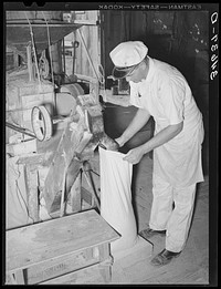 Proprietor of feed mill filling sack with freshly-ground corn meal. Taylor, Texas by Russell Lee