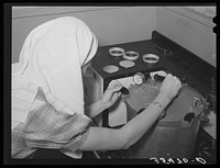 FSA (Farm Security Administration) supervisor giving a demonstration of pressure canning before a group of FSA officials and supervisors at a district meeting at San Angelo, Texas. She is loosening clamps which hold top of pressure cooker securely in place by Russell Lee