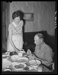 Dinner on ranch of rehabilitation borrower during goat shearing and kidding season. Kimble County, Texas. The man is a neighboring rancher who has been hired to help out with the work at this particular time.  The woman is his wife who is helping out in the house by Russell Lee