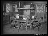 Dining table in Navajo Lodge, Datil, New Mexico. The center of the table which is raised is mounted on an old wagon wheel hub and revolves with the food before those seated around the table. The wheel above the table in olden days supported a hanging lamp. Now it is fitted with electicity by Russell Lee