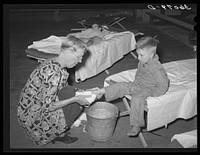 WPA (Work Projects Administration) nursery school attendent washing dirty feet of the children before they their afternoon nap at the Agua Fria migratory labor camp. Arizona by Russell Lee