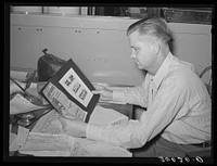Secretary of the United Producers and Consumers Cooperative examining advertising material. Phoenix, Arizona by Russell Lee