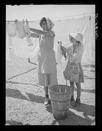 Wife of migratory agricultural laborer and daughter hanging up the wash at the Agua Fria migratory labor camp. Arizona by Russell Lee