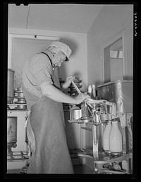 Member of the Casa Grande Valley Farms, Arizona, capping milk bottles by Russell Lee