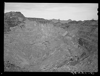 Sacramento Pit copper mine at Bisbee, Arizona. This is a pit 435 feet deep. In 1911 a shaft was sunk into the slopes of the east wall. In 1917 a dynamite charge blew off the top rock of the crown and dredges were worked to excavate the pit's ore bodies. By 1931 the pit floor was too narrow for dredges to work in. The ore was taken out by caving in the walls into the lower mine levels. Between 1917 and 1931 the mine, which covers thity-five acres, yielded 20,843,667 tons of ore. The mine is today abandoned. This development by the Phelps Dodge Company by Russell Lee