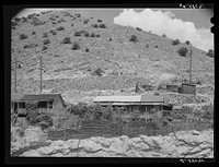 House on side of mountain in Bisbee, Arizona, showing the timber supports needed to keep soil from washing completely away from the house by Russell Lee