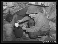 [Untitled photo, possibly related to: Eugene Davis, gold prospector, making a pot of coffee in his shack on his diggings at Pinos Altos, New Mexico] by Russell Lee