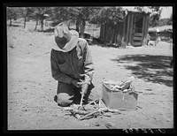 Faro Caudill building a fire to cook dinner while he moves his dugout. Pie Town, New Mexico by Russell Lee